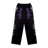 A pair of black and lilac joggers from 22DABE22 with a distressed finish, adjustable waist and leg openings, and oversized unisex fit. Screen prints on both sides and embroidery appliqué at the back pockets add a unique touch to the high-quality blend of 80% cotton and 20% polyester fabric. Pair it with the matching zip jacket for a complete streetwear set.
